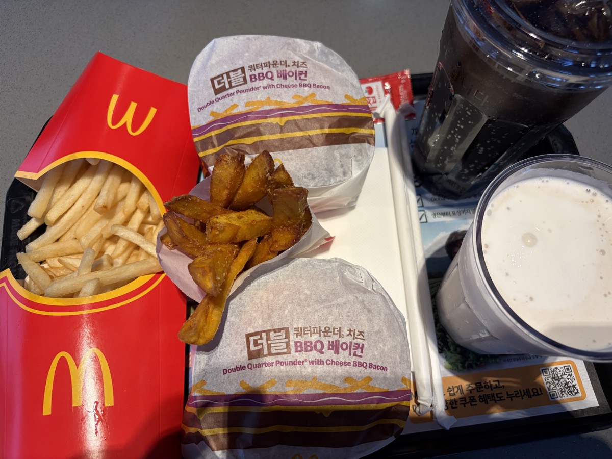 트레이 위에 놓인 버거 두 개, 감자튀김, 고구마 후라이, 음료